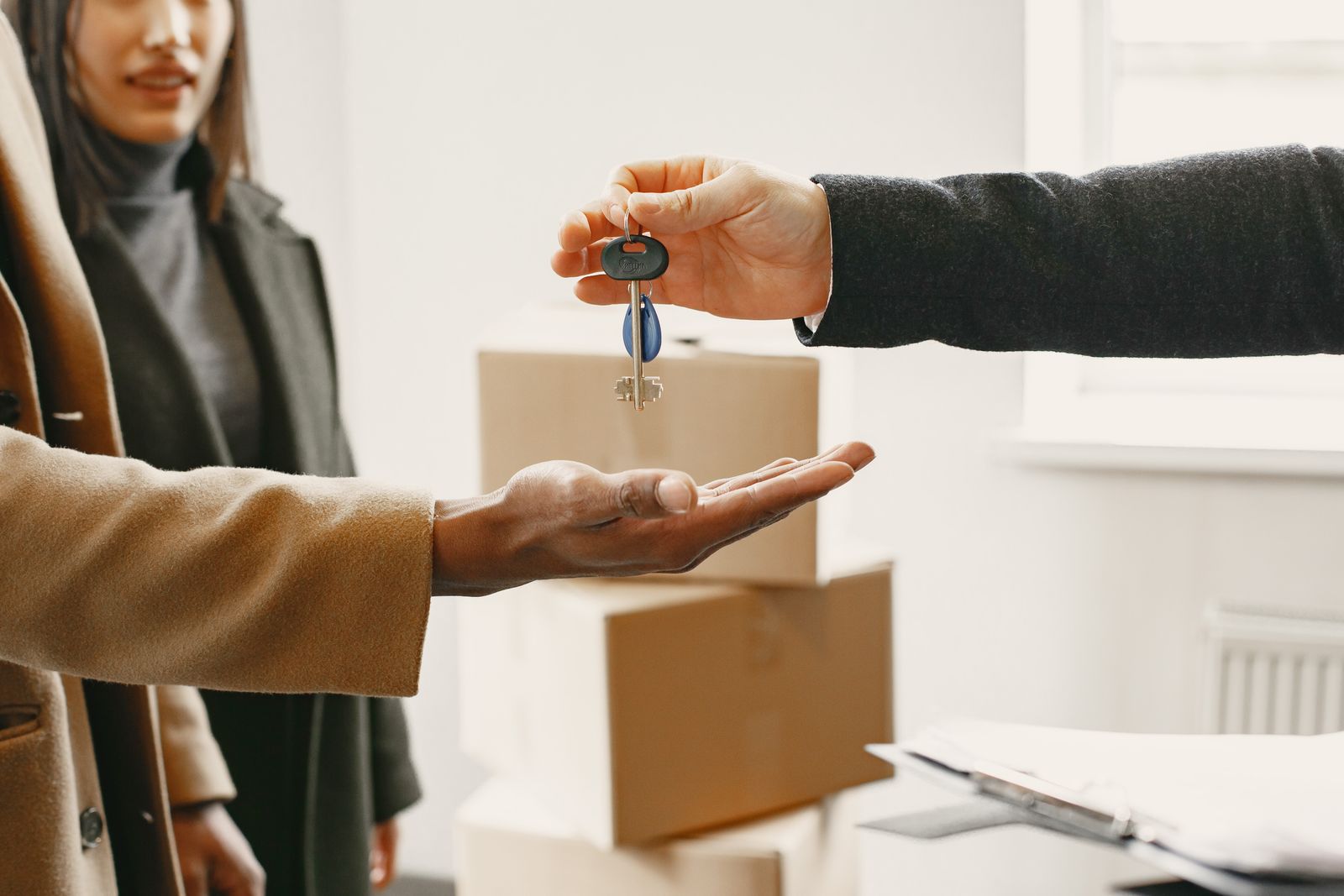 A person receiving the keys to their new home across a stack of moving boxes