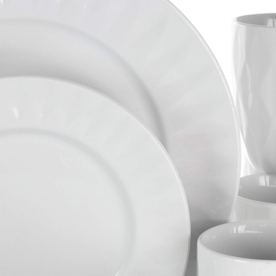 Close-up of Elama Sienna white porcelain dinner and dessert plate rims with a cup and bowls behind