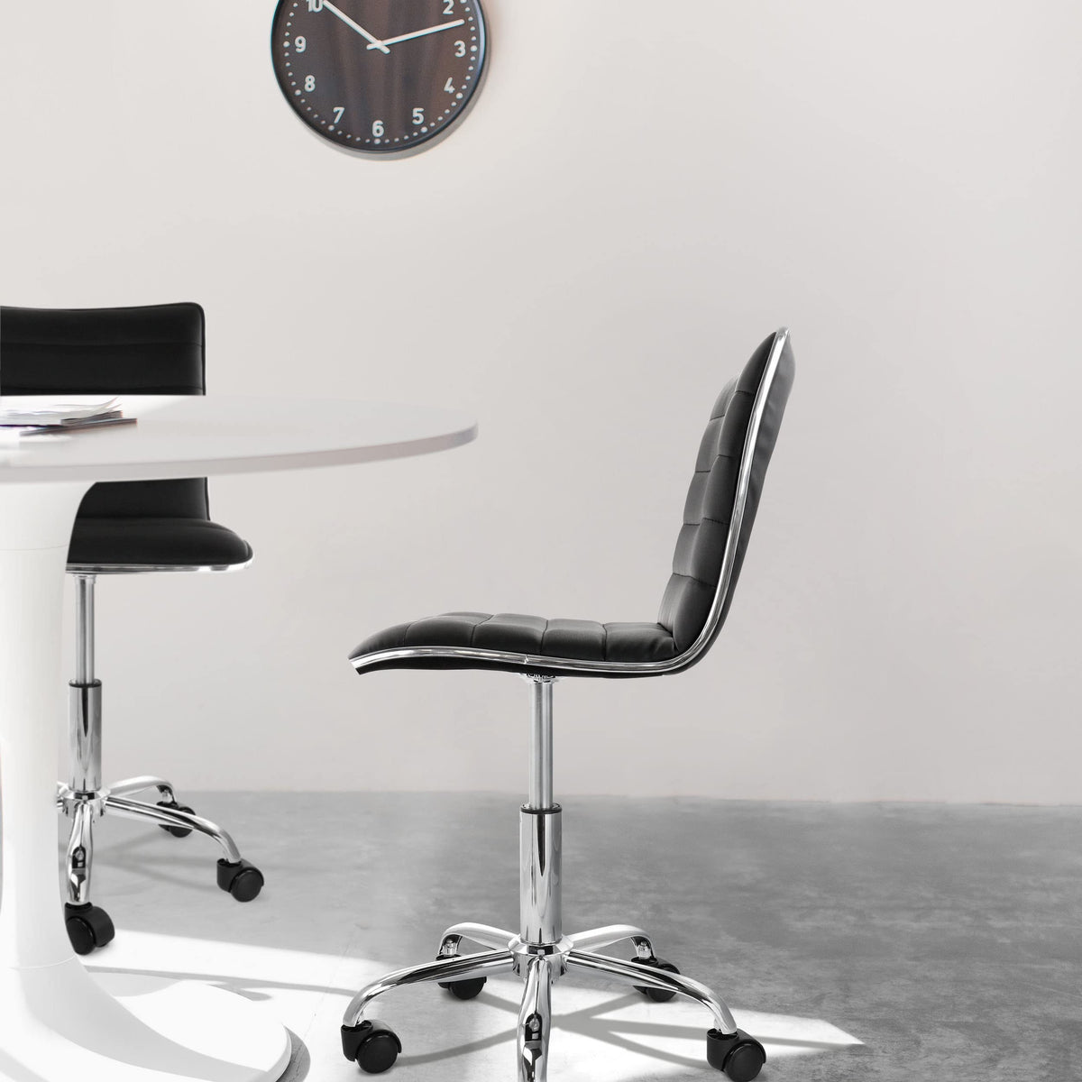 Elama black striped armless rolling chairs at a round white table, lifestyle in a bright dining or meeting space