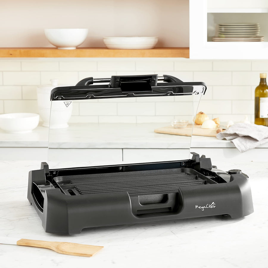 MegaChef indoor grill and griddle on a kitchen counter with the glass lid open and the ridged grill side of the plate facing up