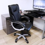 Elama black faux leather office chair with silver base, lifestyle at a home office desk with a monitor and keyboard tray