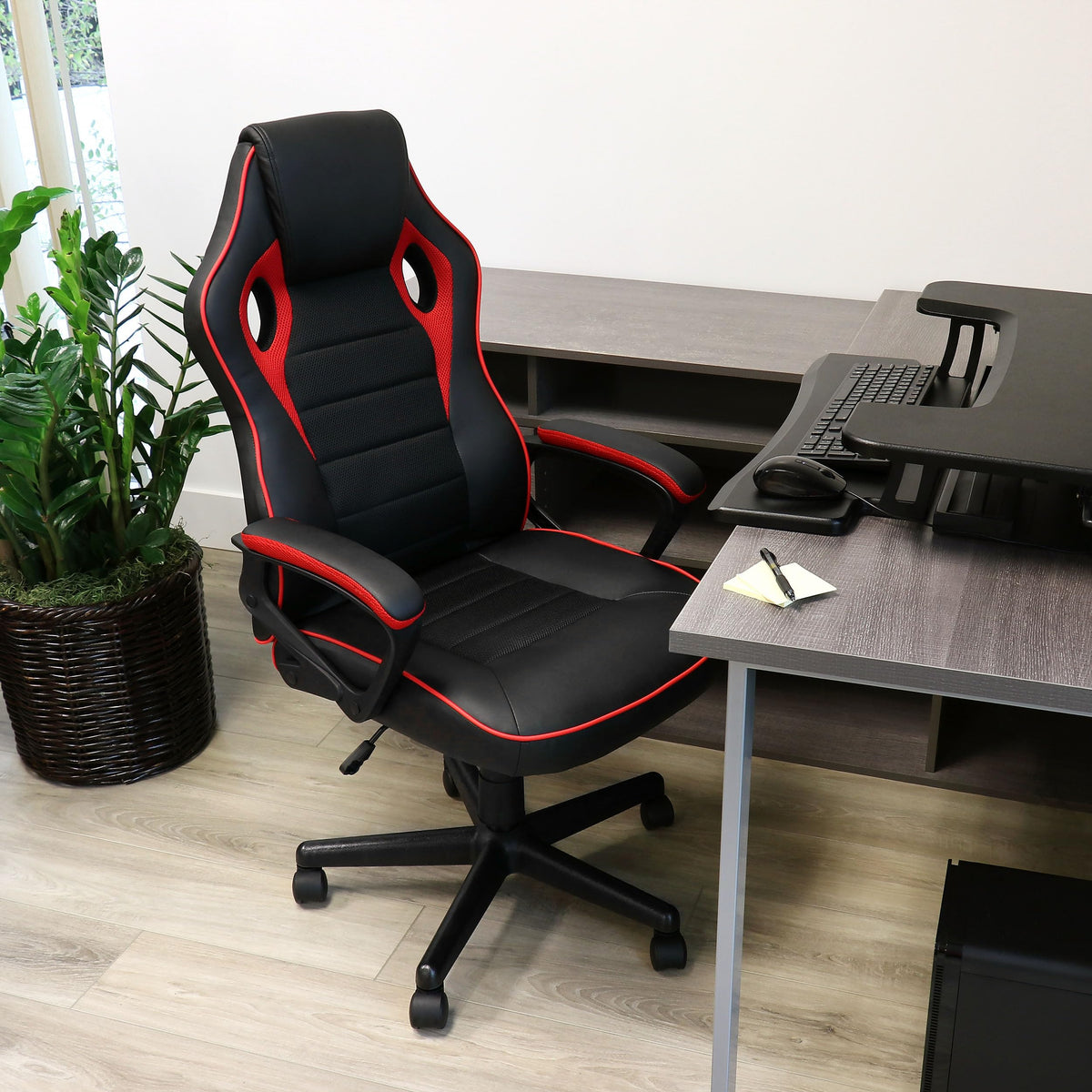 Elama black and red high back office chair, lifestyle at a home office desk with a plant and keyboard tray