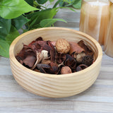 MegaChef light acacia wood bowl filled with dried potpourri on a wood table beside plants and candles