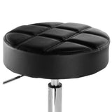 Close-up of the Elama black backless stool seat, round tufted faux leather cushion with the height adjustment lever