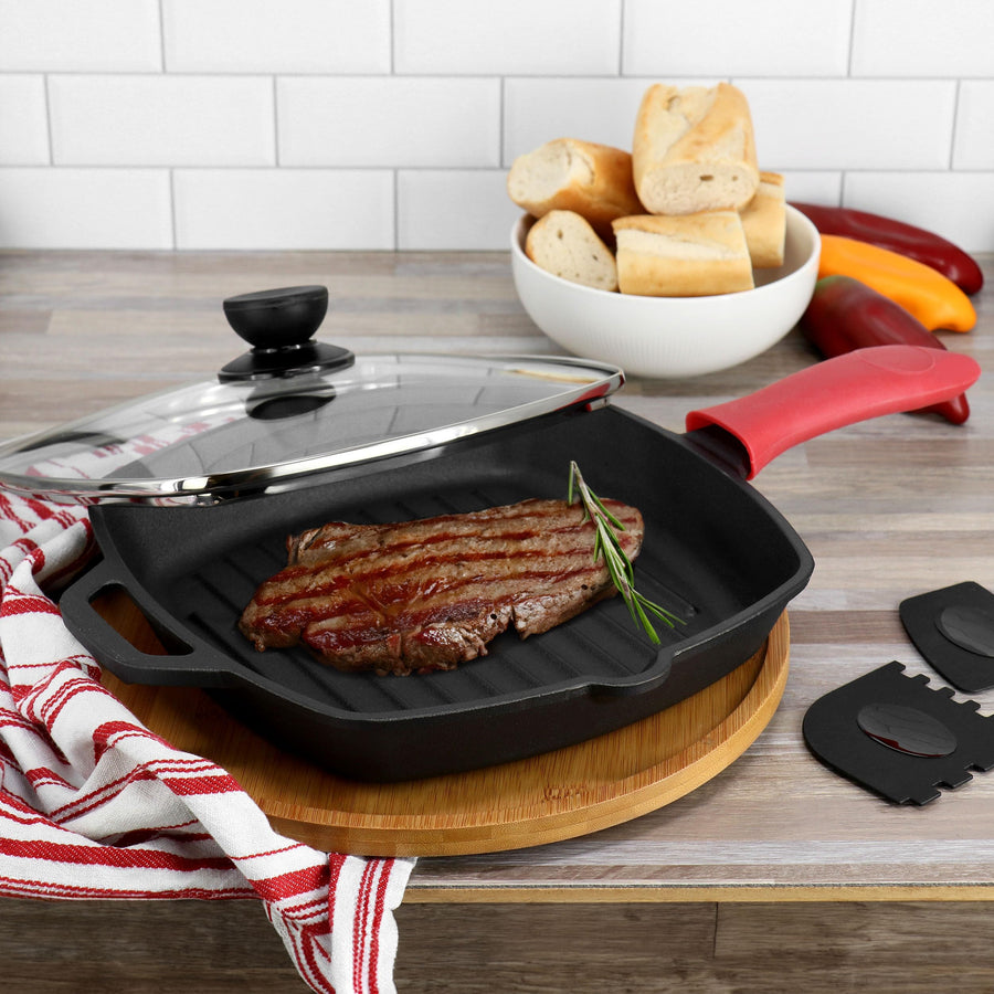 Cast iron grill pan with glass lid searing steak on a kitchen counter