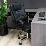 Elama black faux leather high back office chair, lifestyle at a home office desk with a keyboard and plant