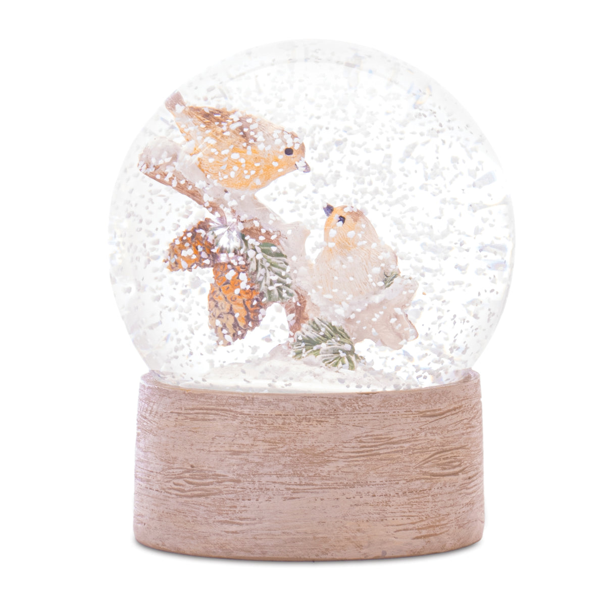 Small snow globe with birds perched on a pine branch with pinecones on a beige faux wood grain base