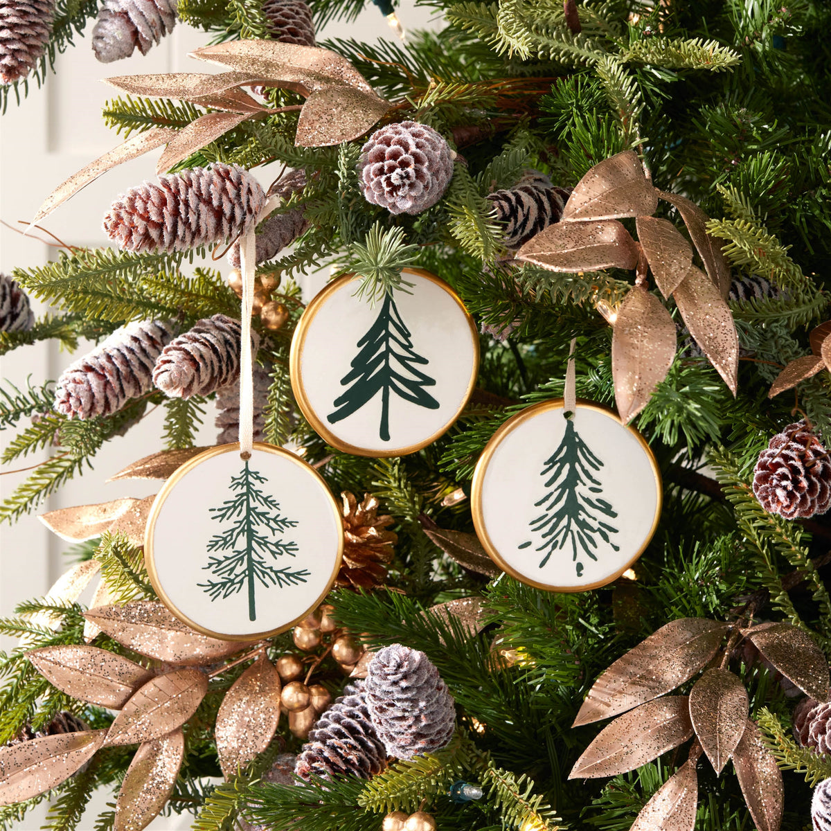 Ceramic Pine Tree Disc Christmas Ornaments hanging on a Christmas tree, holiday decor styling idea
