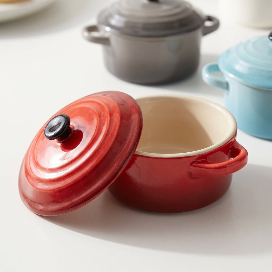 Close-up of the red Crock-Pot Pembury mini casserole with its lid lifted, showing the stoneware glaze and side handles