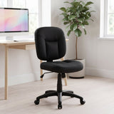Elama armless black task chair at a white desk in a bright home office with a tall plant and large windows