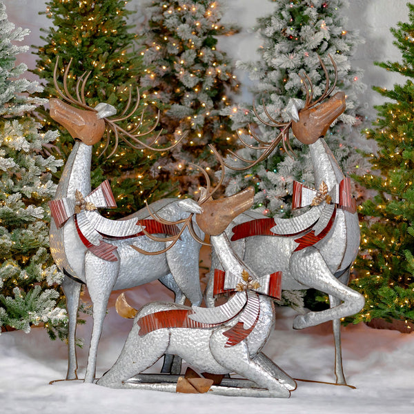 Set of three life size frosted silver galvanized reindeer, standing, leg up, and lying down, each with a red and silver bow and jingle bells