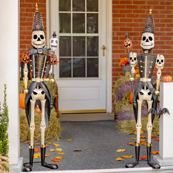 Two 63.5 inch iron skeleton soldiers holding skull and pumpkin staffs, distressed black and white finish