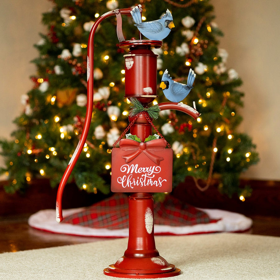 Old style red iron water pump with hanging Merry Christmas sign and blue birds, distressed finish