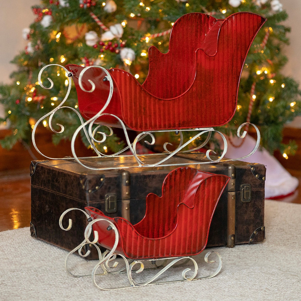 Two Victorian style red iron sleighs with distressed hand painted finish, large and small