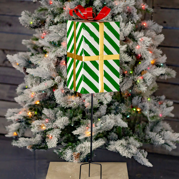Iron Christmas gift box yard stake with green and white stripes, gold ribbon, and red bow