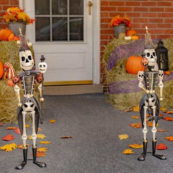 Two 36 inch iron skeleton soldiers holding skull and pumpkin staffs, distressed hand painted finish