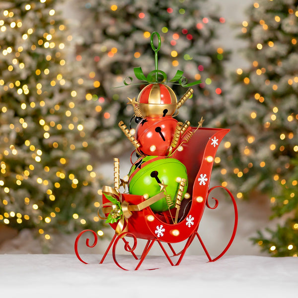 Small iron Christmas sleigh filled with giant red, green, and gold jingle bells and LED lights