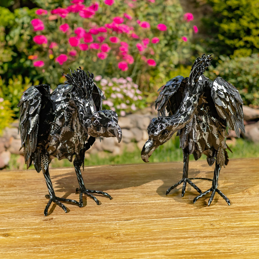 Two galvanized iron vulture sculptures, one head up and one head down, hand painted metallic black