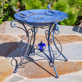 23" Tall Iron Birdbath with Bird Details and Porcelain Globe Accent in Blue "Rome 1945" in a garden