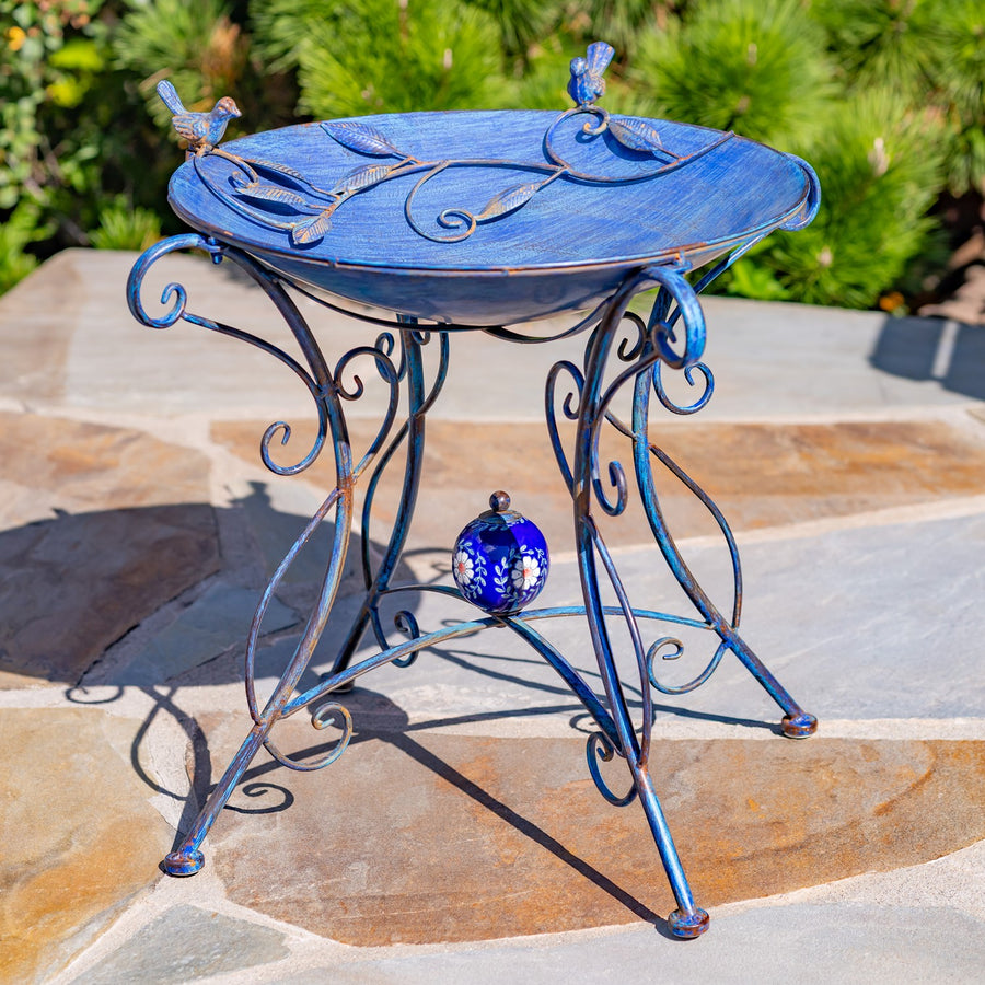 23" Tall Iron Birdbath with Bird Details and Porcelain Globe Accent in Blue "Rome 1945" in a garden