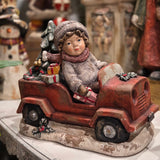 19 inch vintage style boy in a red truck with a Christmas tree and colorful gifts on a snowy base, hand painted polyresin