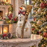 Vintage-style polyresin snowman figurine with a rustic broom, knit cap, and scarf in a distressed hand painted finish