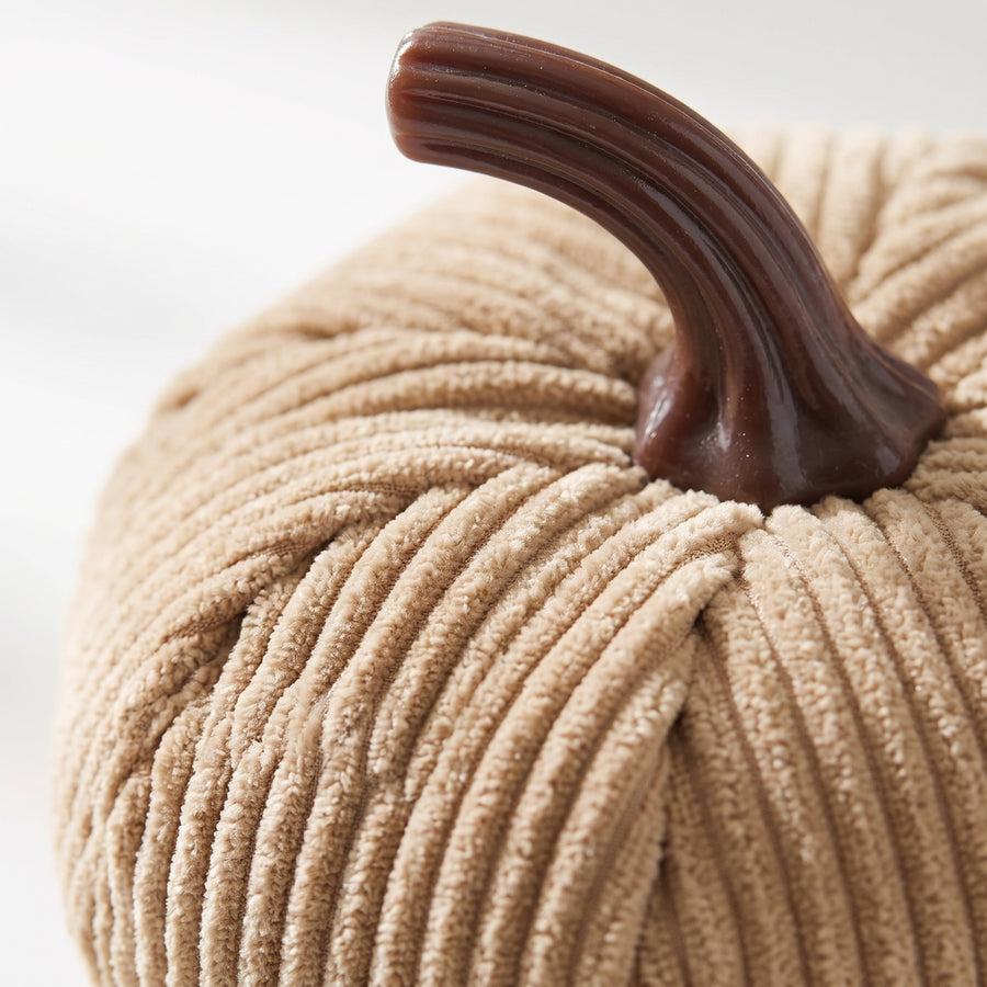 Macro of a plush corduroy pumpkin showing ribbed woven texture and a glossy dark brown moulded resin stem