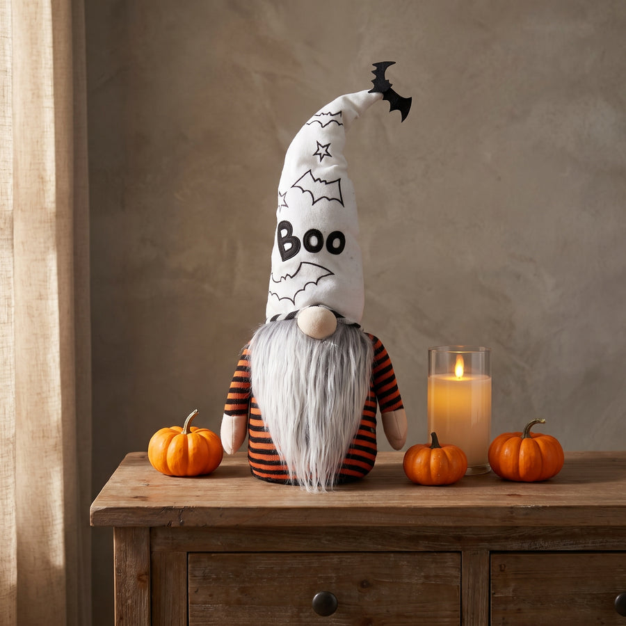 Grey plush ghost gnome on an entry console with small orange pumpkins and a flameless candle for Halloween