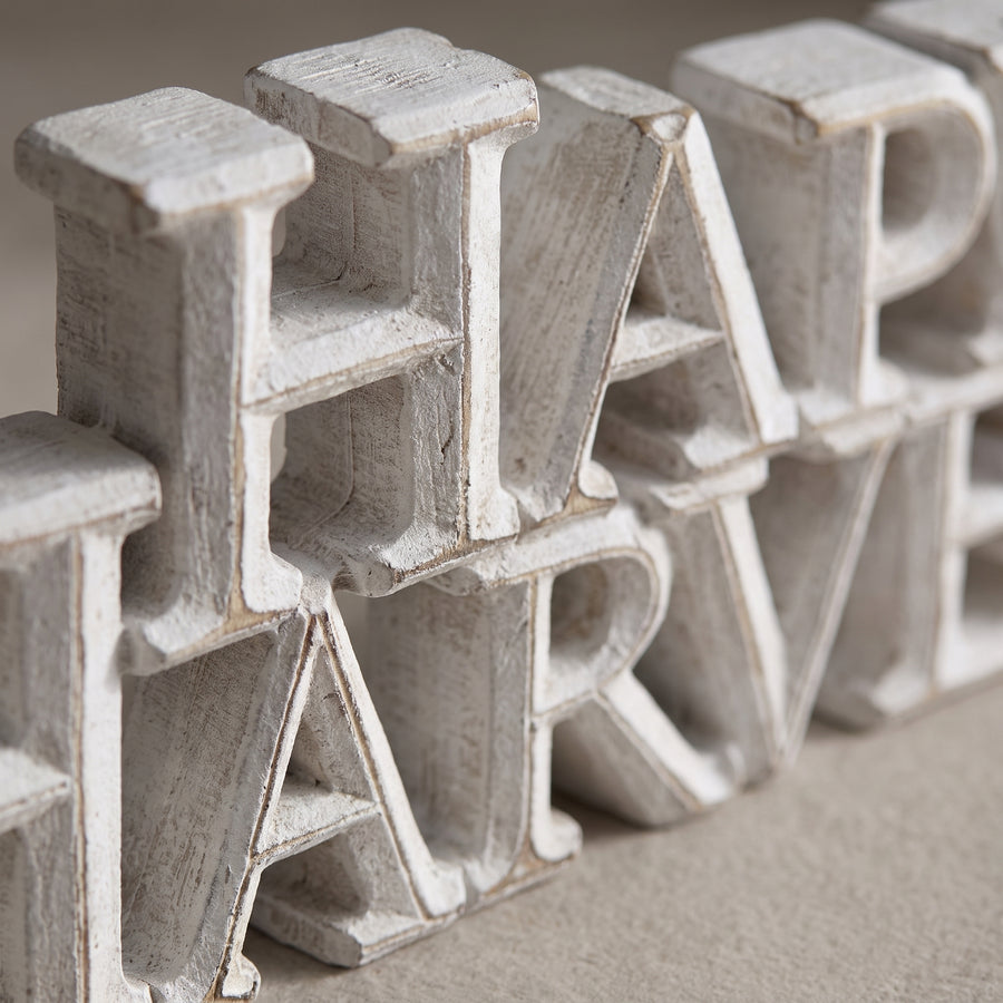 Macro of a white-washed resin sign showing distressed wood-look grain and printed harvest wording