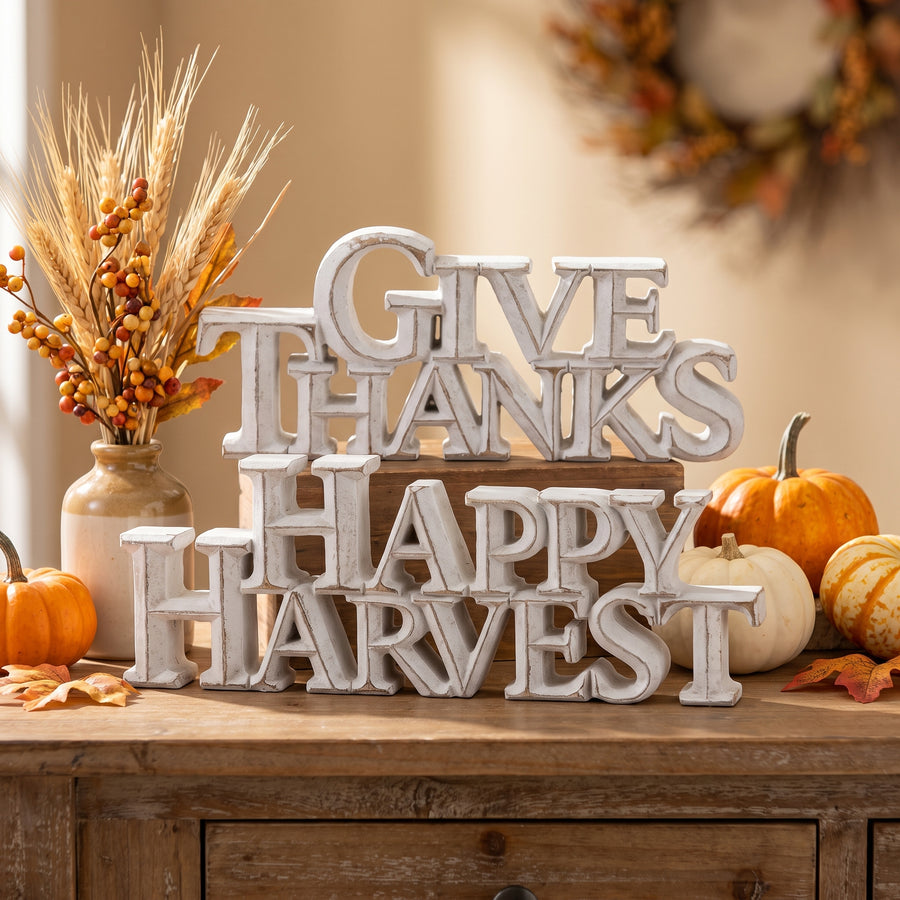 White-washed happy harvest and give thanks signs propped on an entry table with small gourds