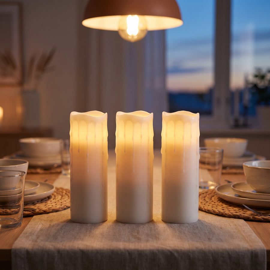 Trio of tall flameless pillar candles glowing at the center of a set dining table in the evening