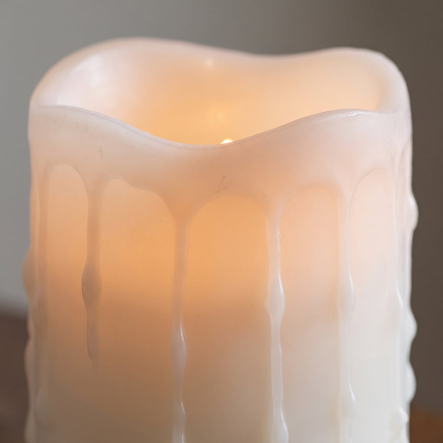 Macro of a white LED pillar candle top showing the hollow dripped-wax rim and a warm glow from inside the column