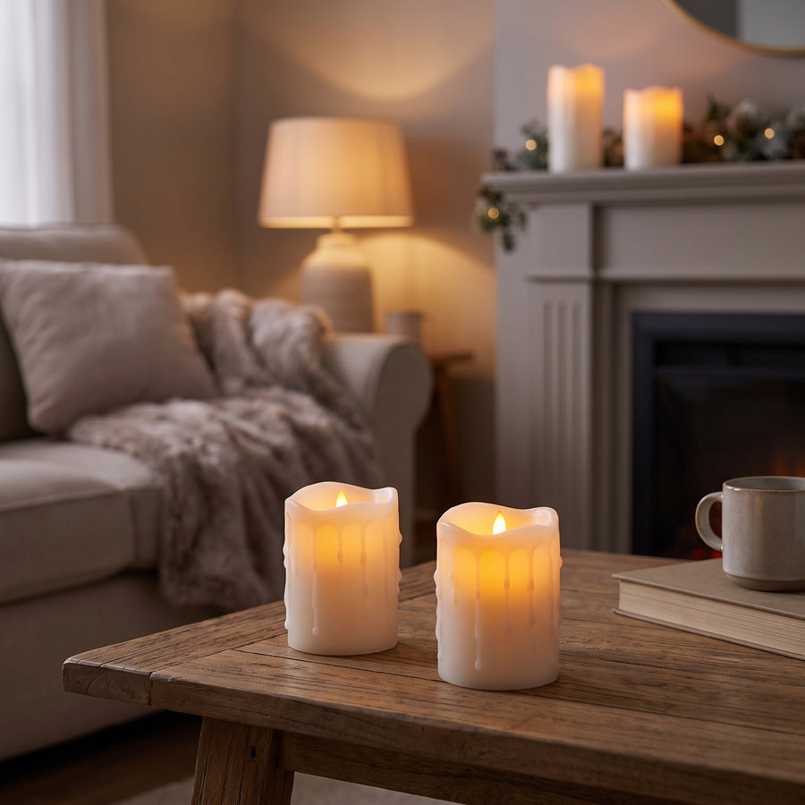 Set of four flameless pillar candles glowing warmly on a coffee table in a cozy living room at dusk