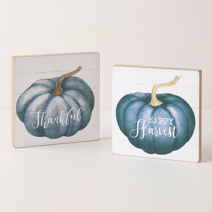 Two square white shiplap signs printed with blue watercolour pumpkins reading thankful and happy harvest, raised studio angle on a plain surface