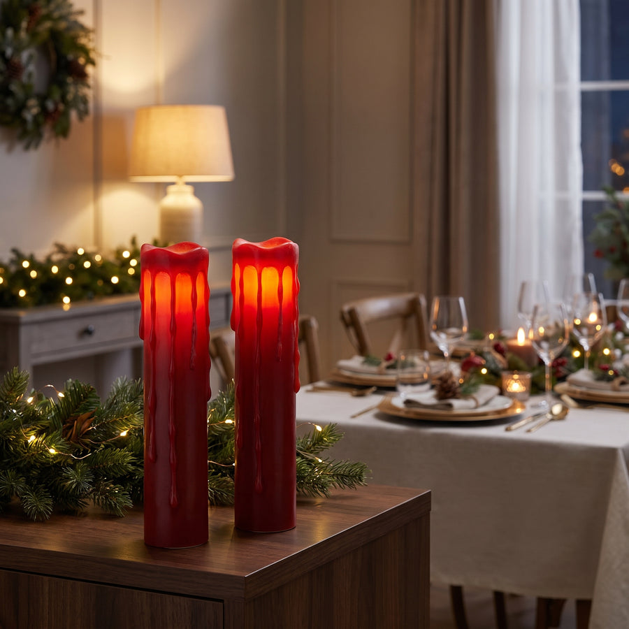 Pair of tall red flameless pillar candles glowing on a holiday sideboard in a festive evening room