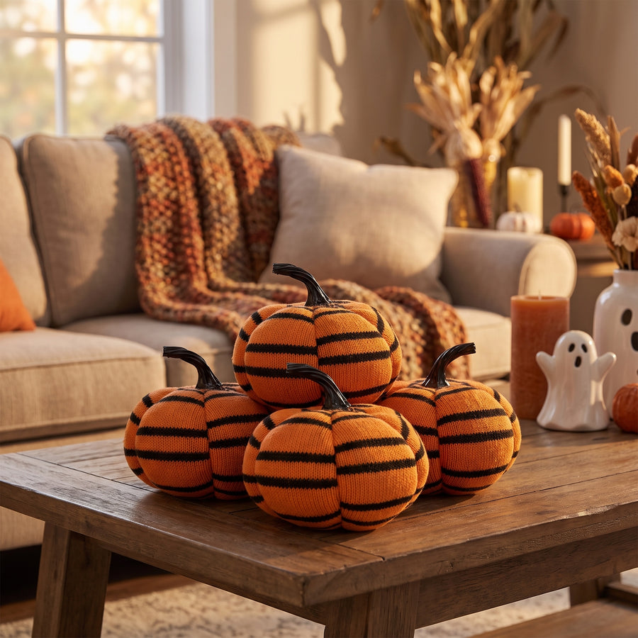 Set of four striped plush pumpkins gathered on a coffee table in a cozy October living room