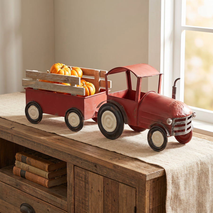 Red iron tractor with a wooden wagon holding small pumpkins on an entry console