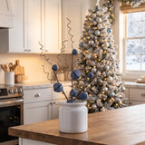 Blue metal jingle bell Christmas stems in a crock on a white farmhouse kitchen island