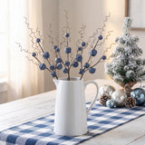 Blue jingle bell stems with curly wire tendrils in a white farmhouse pitcher at Christmas