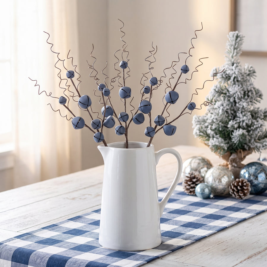 Blue jingle bell stems with curly wire tendrils in a white farmhouse pitcher at Christmas