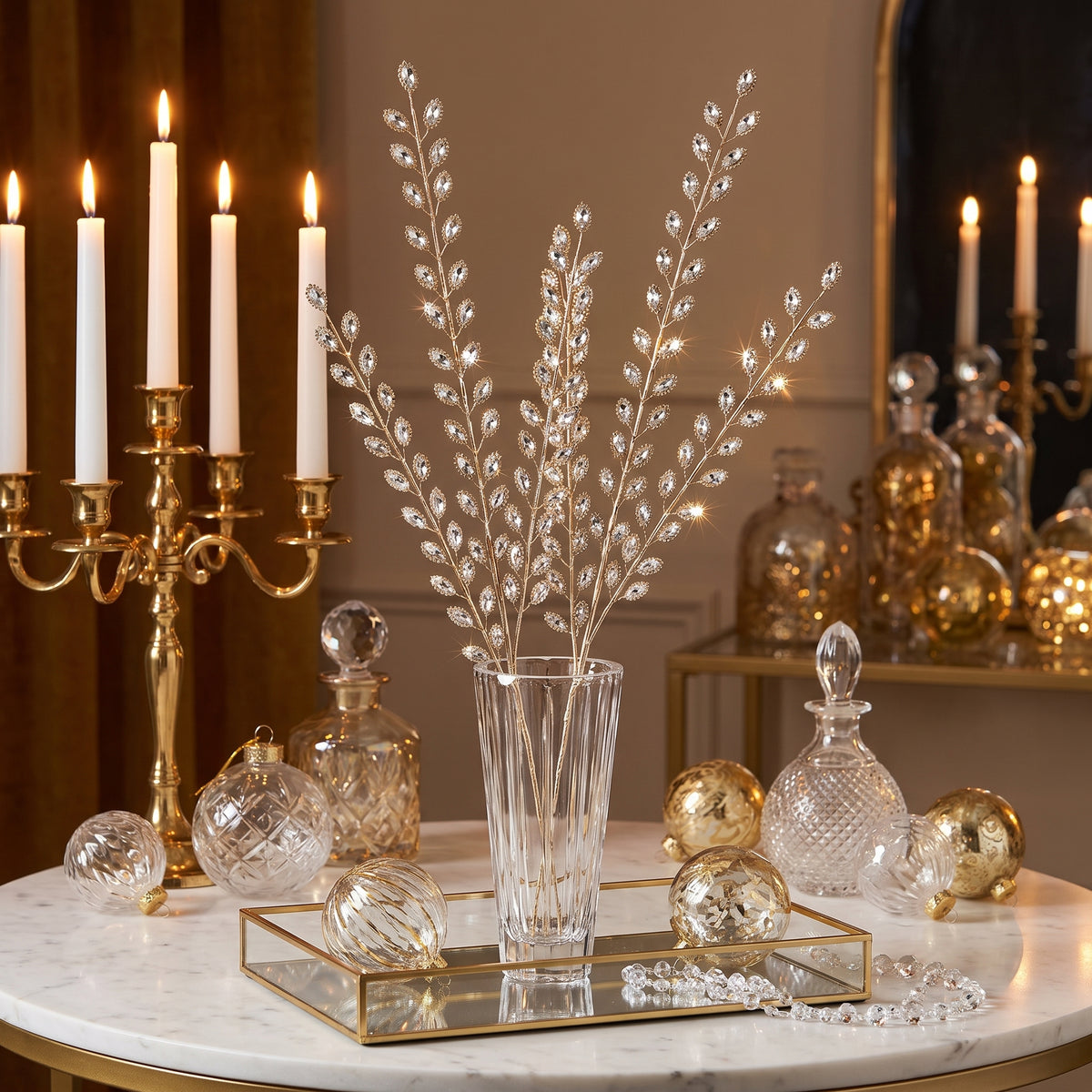 Clear jewel leaf sprays on gold stems in a crystal vase with gold candelabra at Christmas