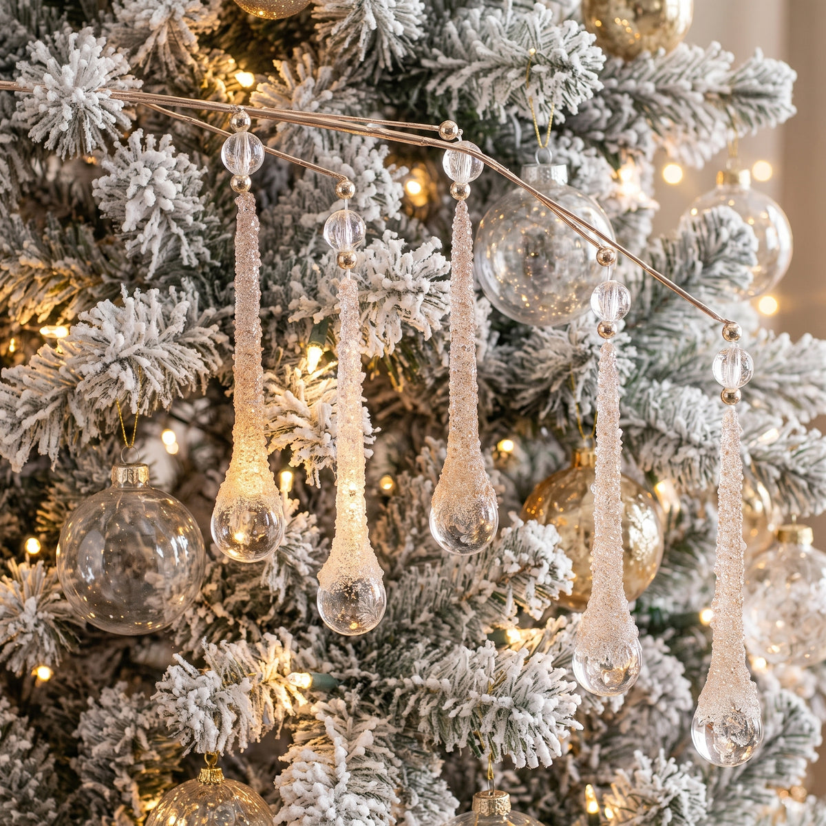 Clear glittered teardrop icicle sprays hanging on a white flocked Christmas tree