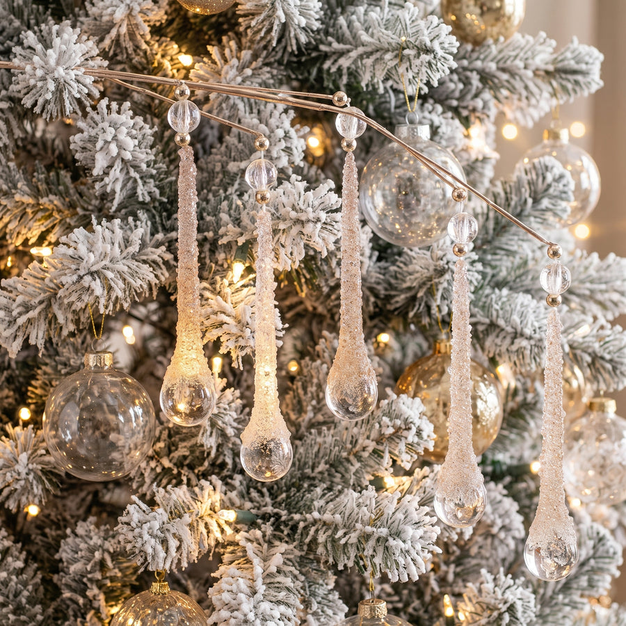 Clear glittered teardrop icicle sprays hanging on a white flocked Christmas tree
