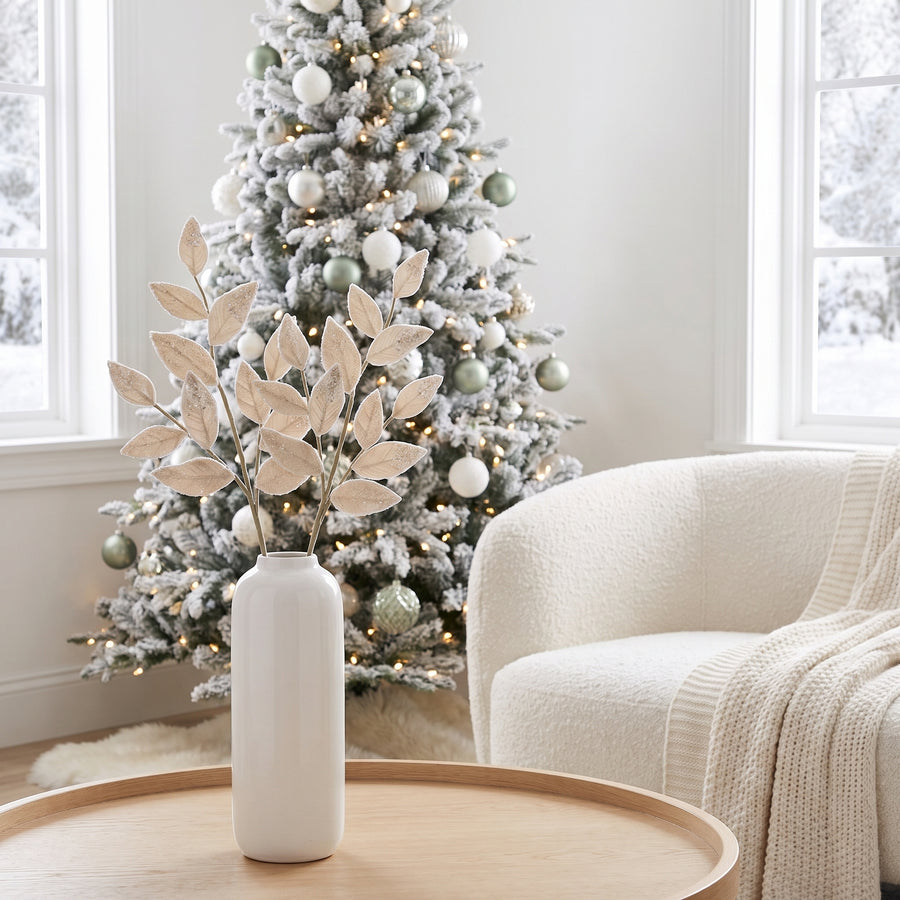 Cream frosted leaf Christmas sprays in a white vase in a Scandinavian white living room