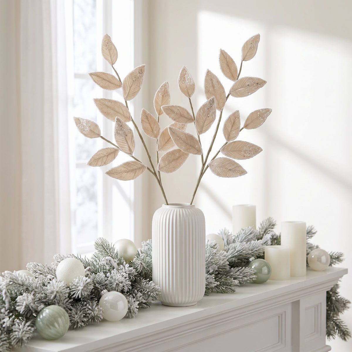 Cream beaded leaf sprays on sage green stems in a white vase on a frosted Christmas mantel