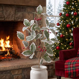Frosted holly and berry Christmas sprays in a crock on the hearth of a woodland lodge