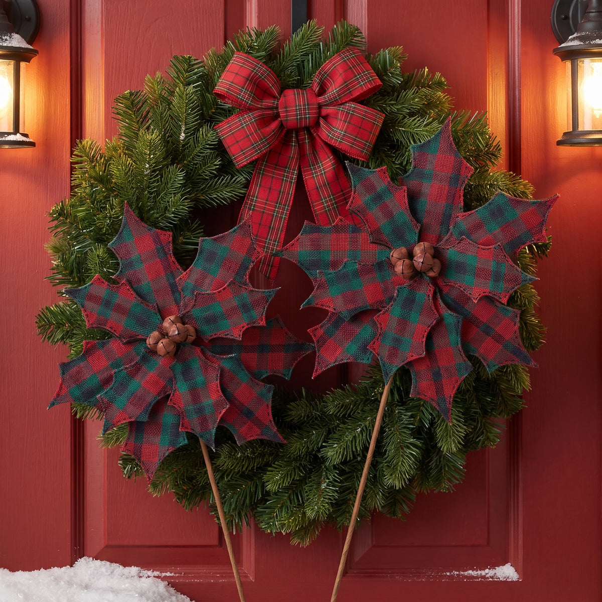 Red and green plaid poinsettia stems with jingle bell centers in a wreath on a red farmhouse door