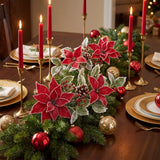 Poinsettia and holly sprays with pinecones and berries in an evergreen table garland with red candles