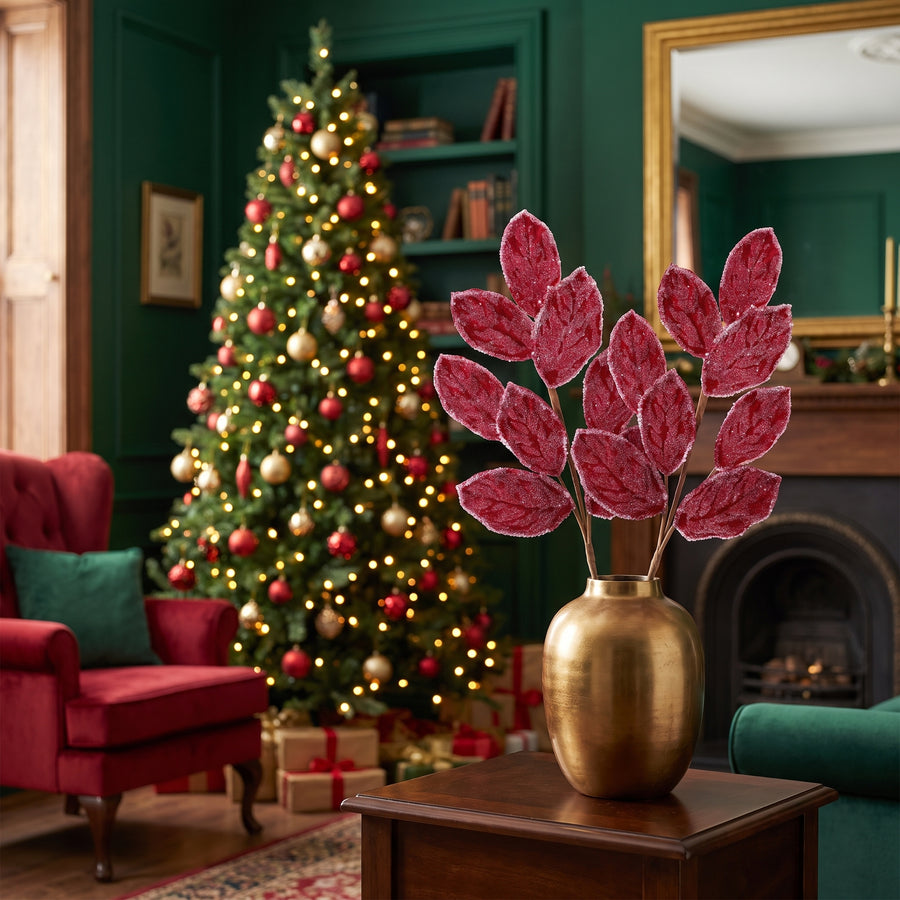 Crimson magnolia leaf Christmas sprays in a gold vase in an emerald green traditional living room