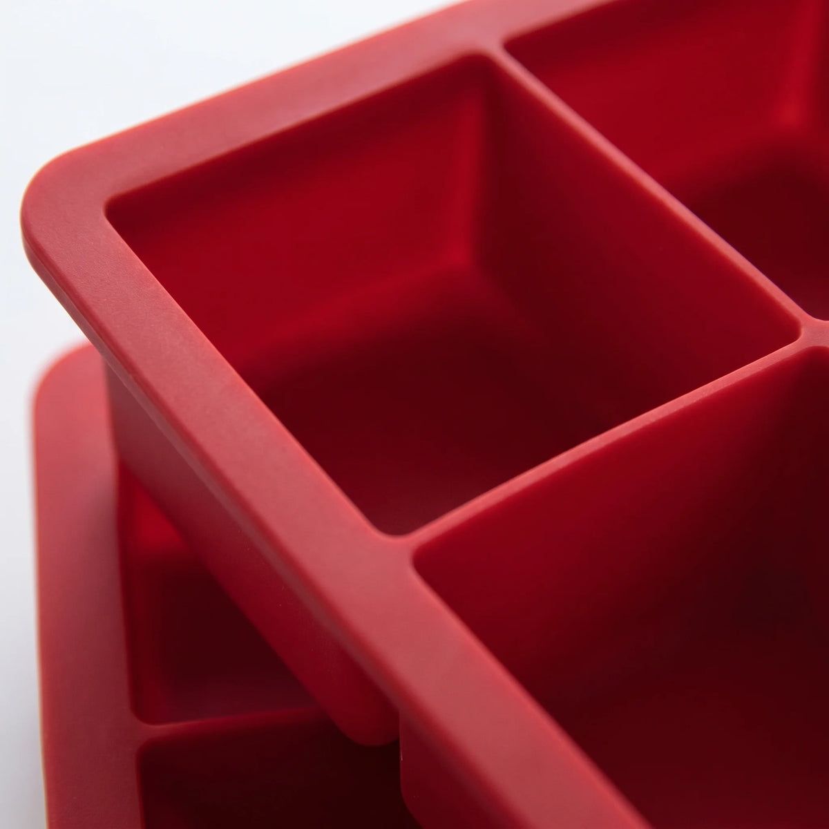 Close-up of the large square wells and thick flexible walls of a red silicone ice cube tray, Houdini